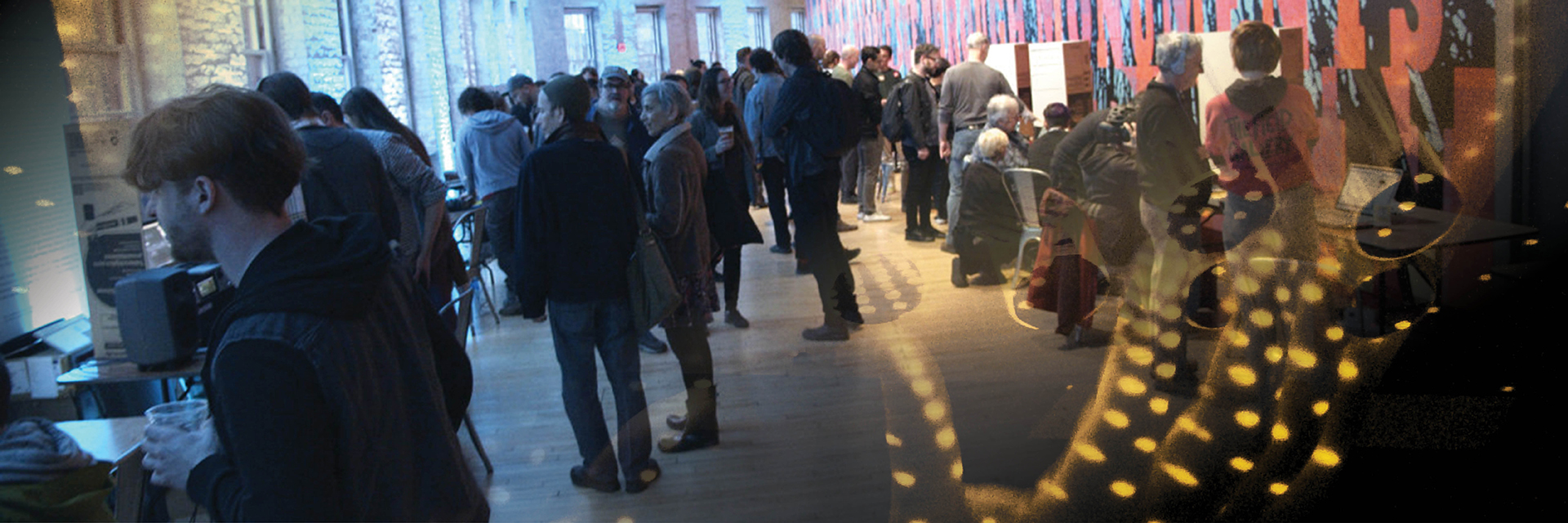 A crowd browses a gallery of different music technology projects.
