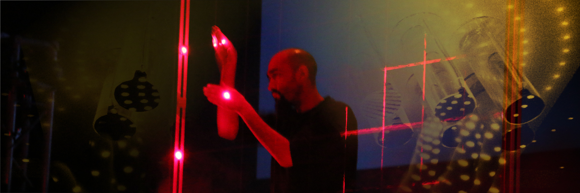 A man playing a set of criss-crossing red lasers within a square frame like a stringed instrument.