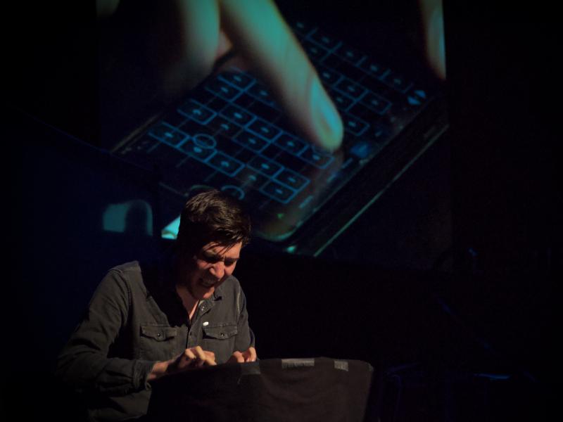 A man playing the Geoshred application on his iPhone in front of an audience.
