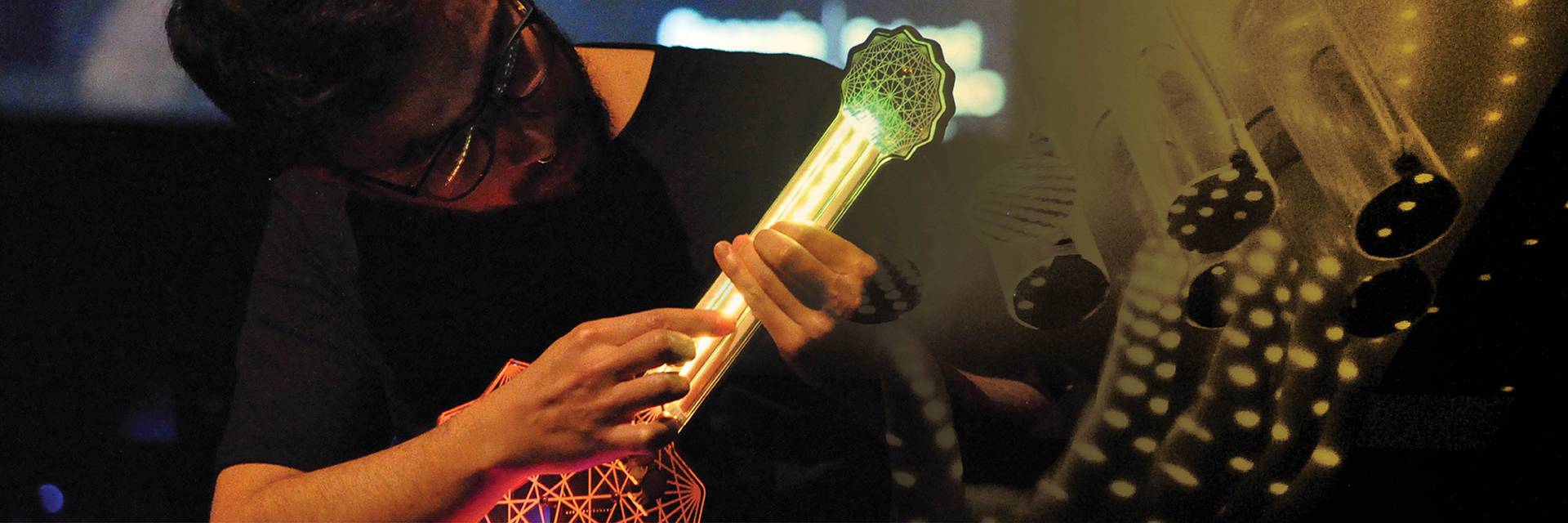 A Guthman contestant plays a guitar-like instrument with LED lights.