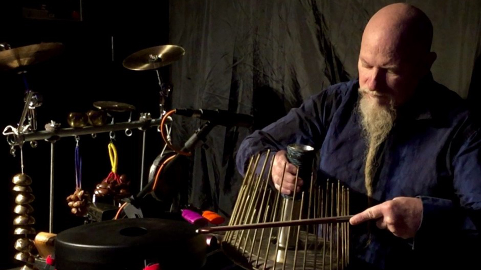Klimchak playing a created instrument created with rods and a stem running through the middle.