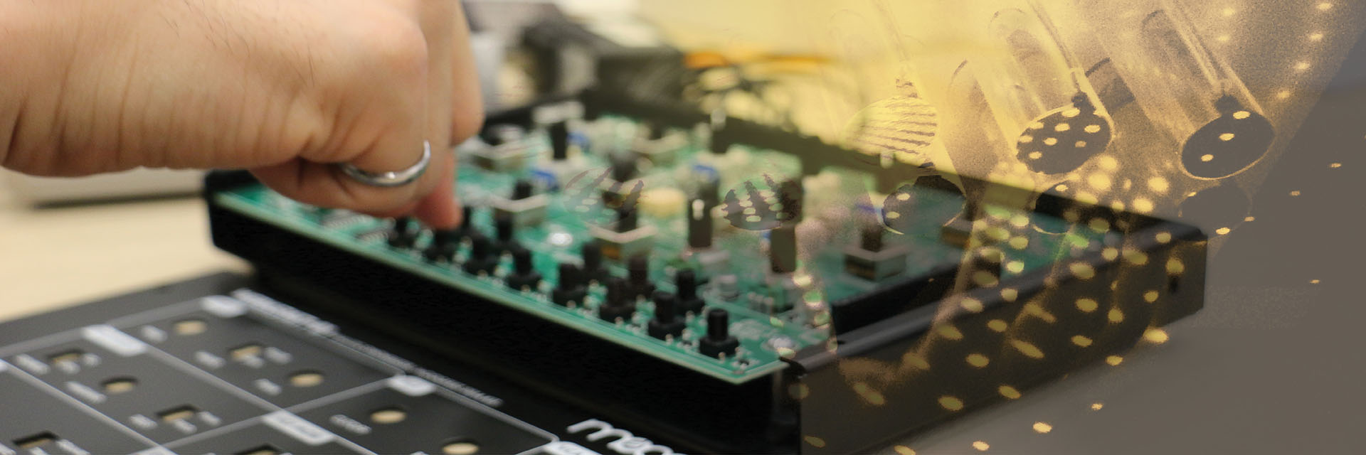 A student's hands working on a partially disassembled Moog synthesizer, with an exposed circuit board.
