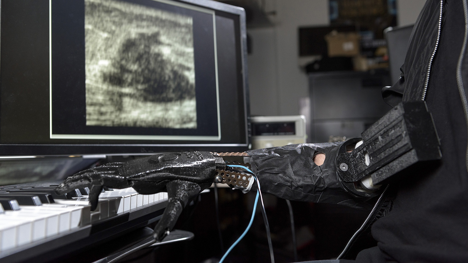 A robotic hand playing music on a keyboard.